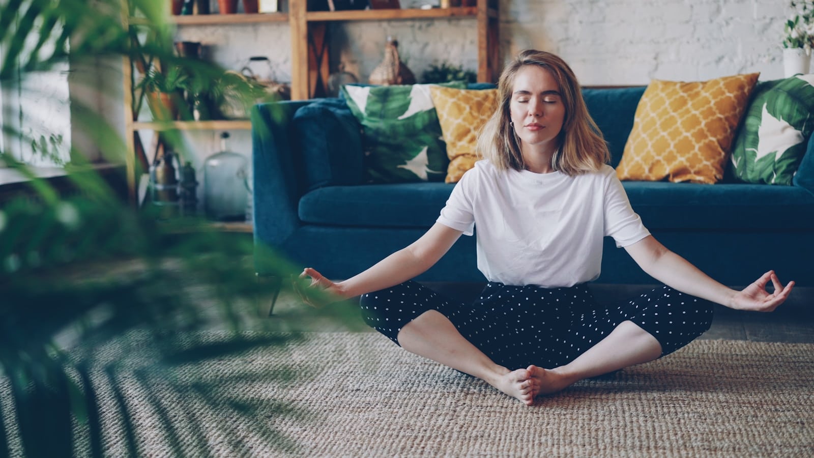 Woman meditating cross-legged on the floor at home.